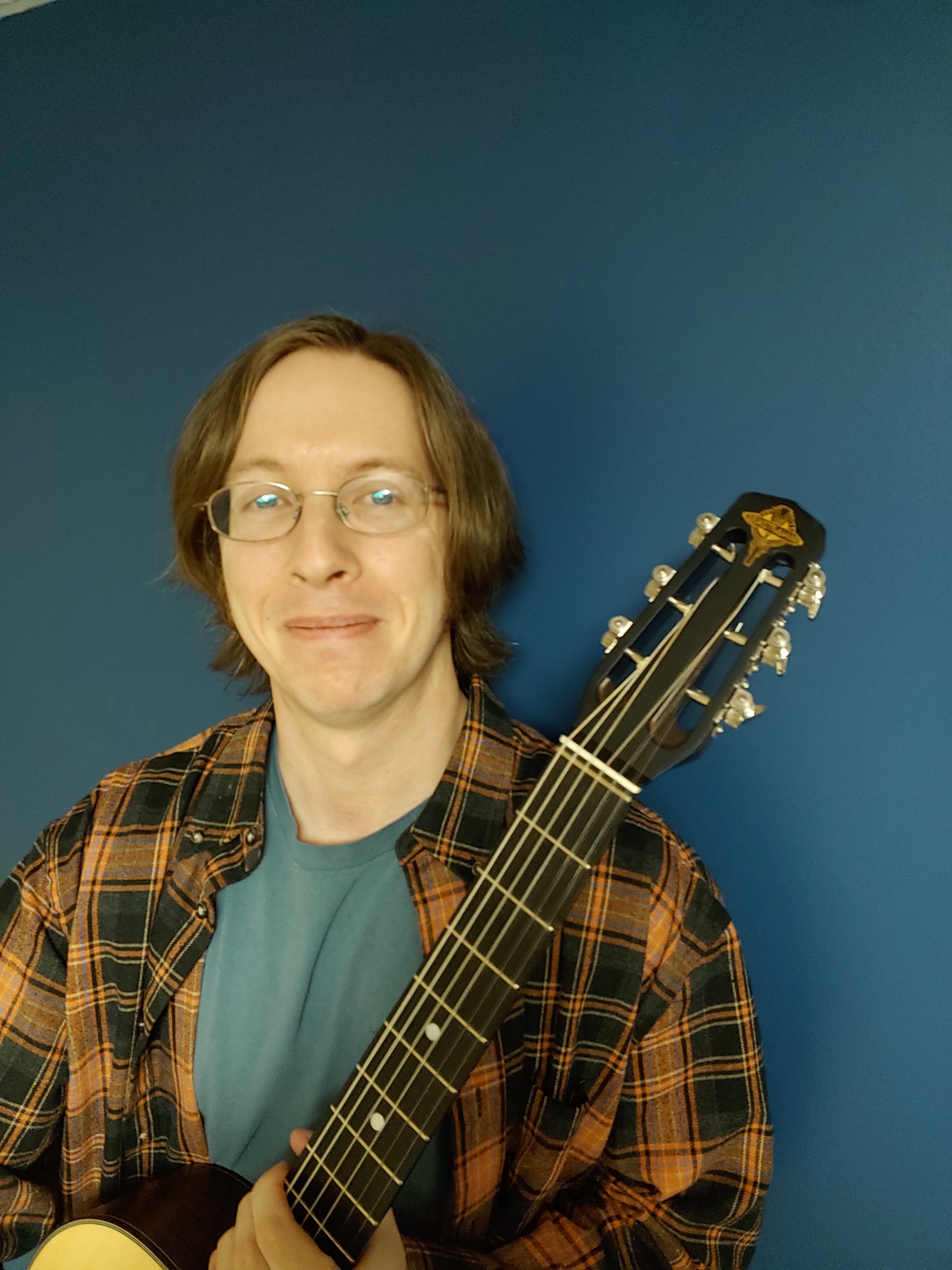 The author, Joe, holding a Selmer-style acoustic guitar with most of the neck and headstock visible.